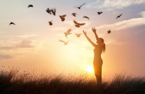 hopeful woman releasing birds in a meadow