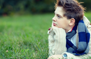 boy lying on grass and daydreaming