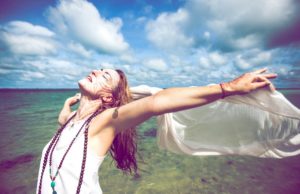 free spirited woman holding a white scarf behind herself midair