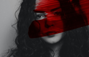 Black and white image of woman's face with red paint across it