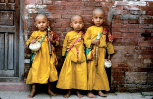 3 Buddhist children attired in ochre robes