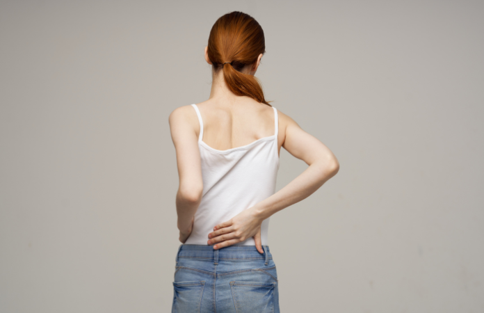 young woman with her hand on her back in pain